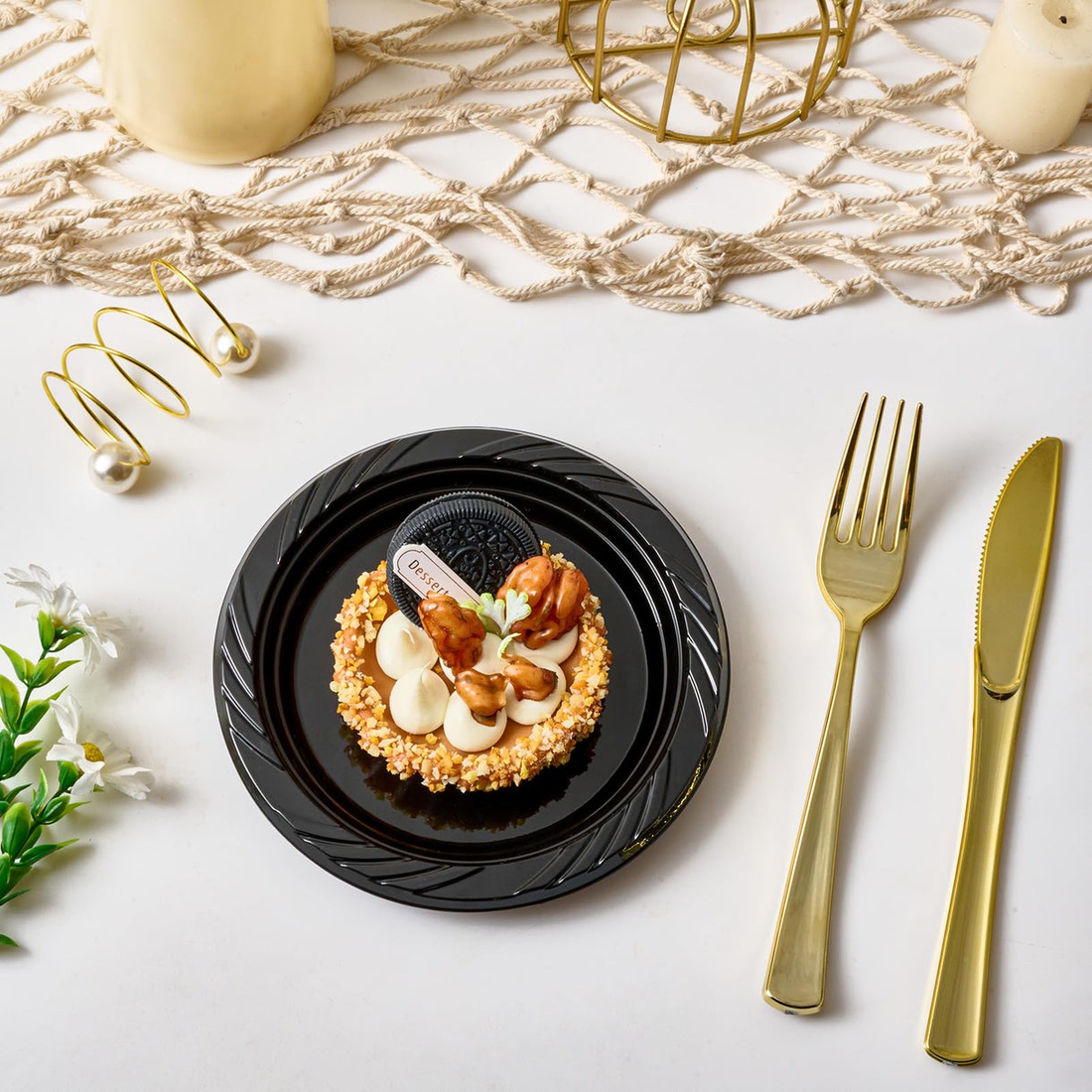 A gourmet dessert on a black Jolly Chef plate, topped with nuts and cream, surrounded by elegant gold cutlery and decorative elements.