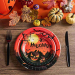 A Halloween-themed table setting with a decorative plate featuring carved pumpkins, surrounded by autumn leaves and mini pumpkins.