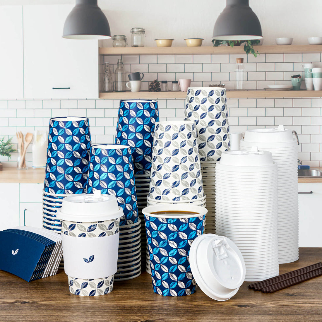 A collection of patterned Jolly Chef paper coffee cups and lids in blue and white, arranged neatly on a wooden kitchen table.