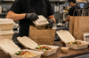 Restaurant worker packing compostable food containers and paper takeout bags in a kitchen