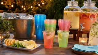 Neon plastic cups at an adult backyard party drink station with mocktail dispensers, ice, and citrus garnishes