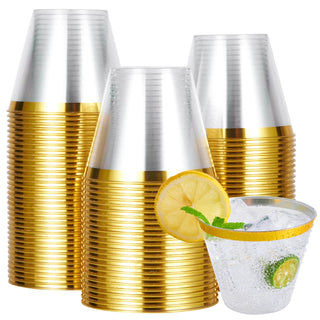 A stack of Jolly Chef Gold&Rose&Silver Rim Plastic(PS) Cups beside a clear glass filled with ice, a lemon slice, and mint leaves.