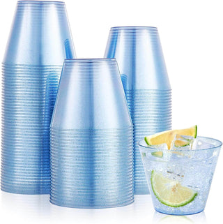 A set of three stacked blue plastic cups beside a glass filled with ice and a lime wedge.