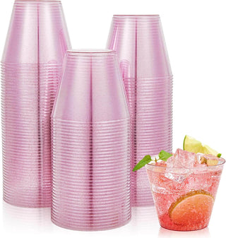Three stacked pink Jolly Chef disposable cups beside a glass filled with a colorful drink, ice, lime, and mint garnish.