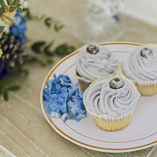 Three lavender frosted cupcakes with blueberries on Jolly Chef Gold Rim Plastic Plates(51 sets), surrounded by blue hydrangeas and greenery.