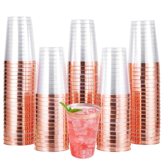 A group of stacked Jolly Chef Gold&Rose&Silver Rim Plastic(PS) Cups  with copper bottoms surrounding a glass of pink drink garnished with mint leaves.