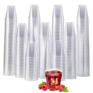 A stack of clear disposable Jolly Chef plastic cups with a small dessert cup filled with raspberry jelly and fresh raspberries in front.