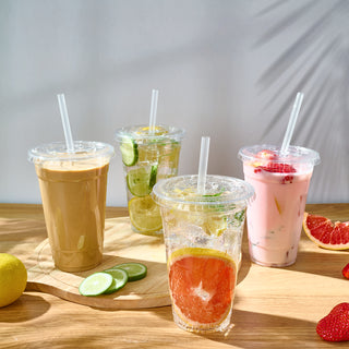Four refreshing drinks on a wooden board: iced coffee, sparkling lime, lemon soda, and fruity pink beverage, surrounded by citrus slices.