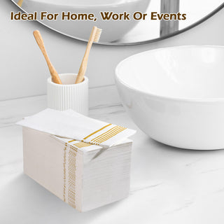 A stack of Jolly Chef 3 Ply Golden Stripe Classic Paper Napkins are placed on the table of the washroom next to the sink