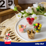 Clear glitter dessert cups with berries, gummies, nuts, and candies on a white plate. Chef mascot and calendar in background.