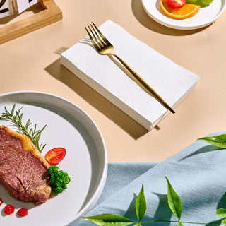 Jolly Chef 3 Ply Classic Napkins placed next to a steak plate and a fork on the top of it