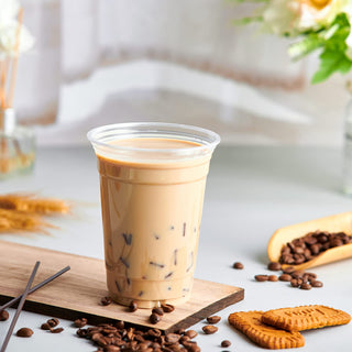 Crystal clear PET plastic cup filled with iced coffee, surrounded by coffee beans and biscuits.