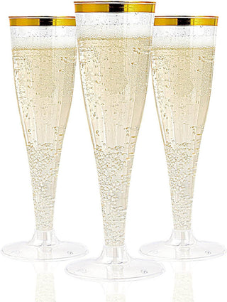 Three elegant Jolly Chef 4.5oz Clear Gold Rim Champagne Flutes filled with bubbly champagne, featuring gold rims and reflecting light, set against a white background.