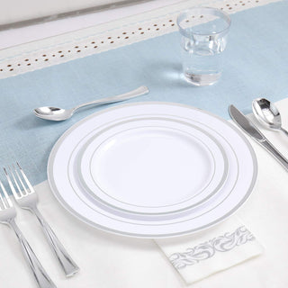Elegant table setting with white and silver plates, silverware, glass of water, and decorative napkin.