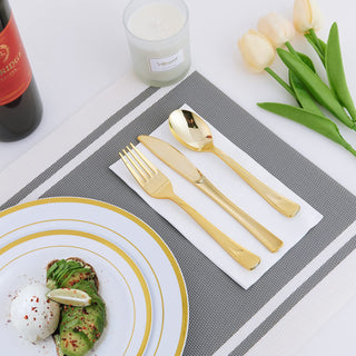 Elegant gold cutlery set on a table with avocado toast, wine, and tulips.