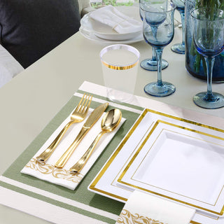 Elegant table setting: gold flatware, white and gold plates, blue goblets, and a striped placemat.