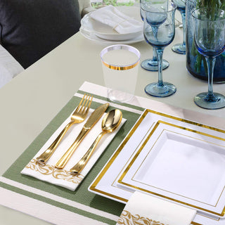 Elegant table setting with gold-rimmed plates, cutlery, and blue glassware.