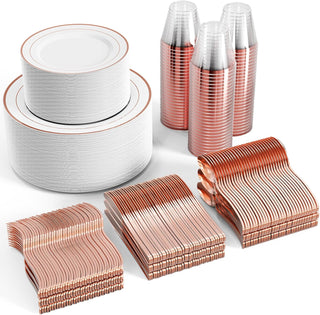 Rose gold party supplies: plates, cups, forks, knives, and spoons stacked on a white background.