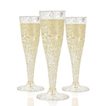 Three 4.5 oz plastic champagne flutes filled with bubbly champagne and adorned with gold glitter.