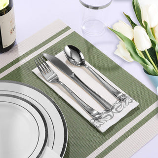 Elegant table setting: silver cutlery on a napkin, white plates, wine bottle, and white tulips.