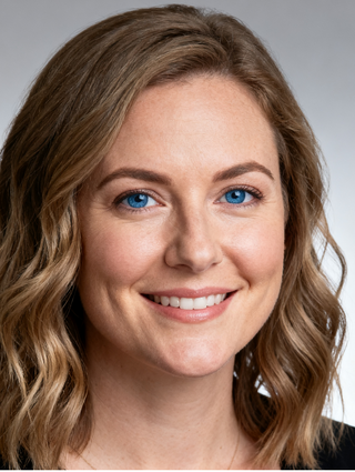 Professional headshot of a smiling woman with bright blue eyes and wavy blonde hair.