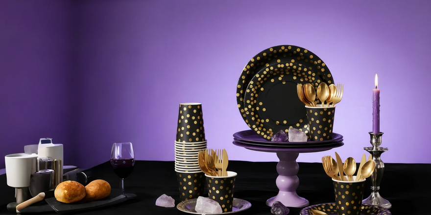 Black and gold party decorations: plates, cups, and gold cutlery.