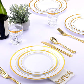 Elegant table setting with gold-rimmed plates, glasses, and cutlery on a white tablecloth.