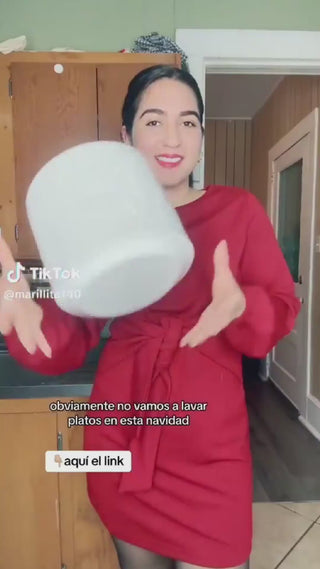 A person in a red dress playfully tosses a large pot while standing in a kitchen, suggesting fun over chores this holiday season.