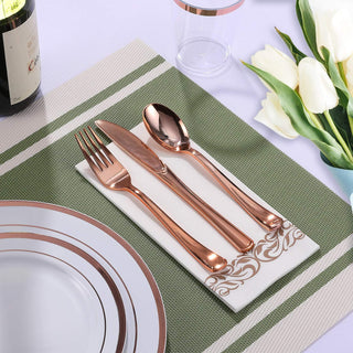 Elegant rose gold cutlery set on a napkin with white plates, wine, and tulips for a sophisticated table setting.