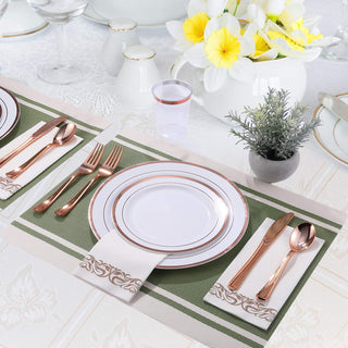 Elegant table setting with white and gold dinnerware, rose gold flatware, flowers, and placemats.