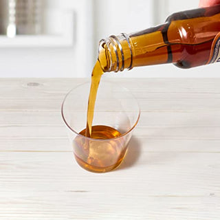A hand pours amber liquid from a bottle into a clear Jolly Chef plastic cup on a wooden surface.