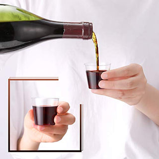 A person pours red wine from a bottle into a small Jolly Chef plastic cup held in their other hand, set against a simple white background.